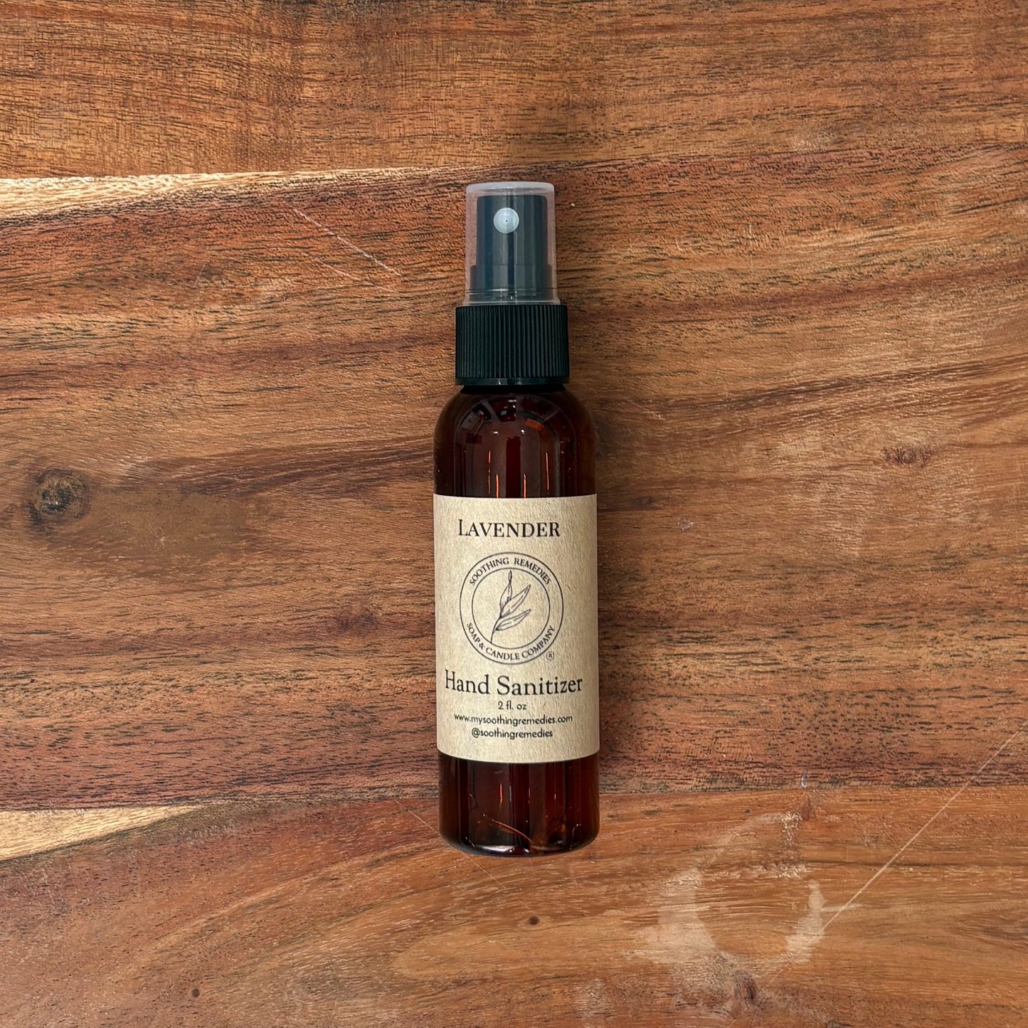 A small bottle of lavender hand sanitizer sits on a large wooden cutting board.