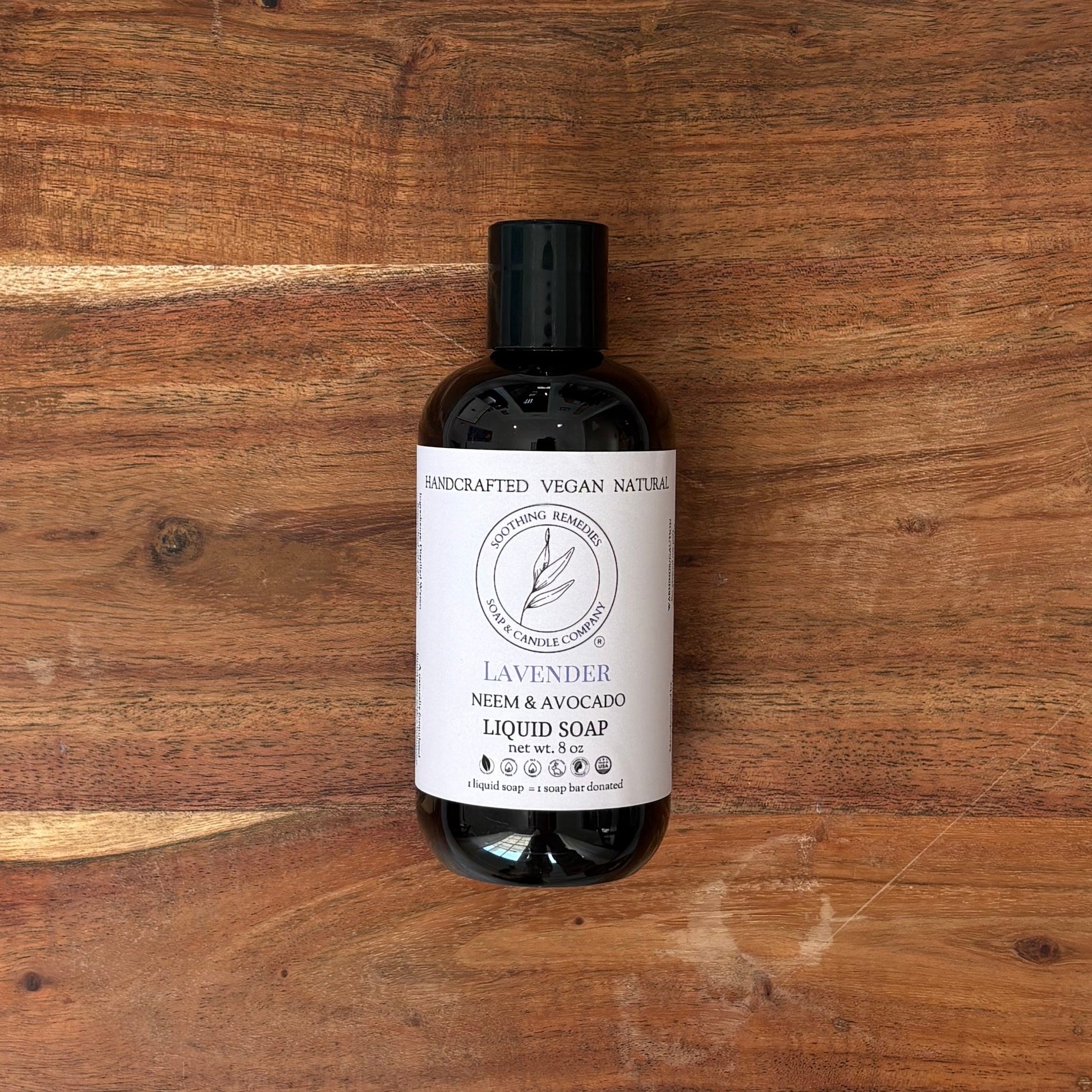 A bottle of lavender neem soap sits on a wooden board