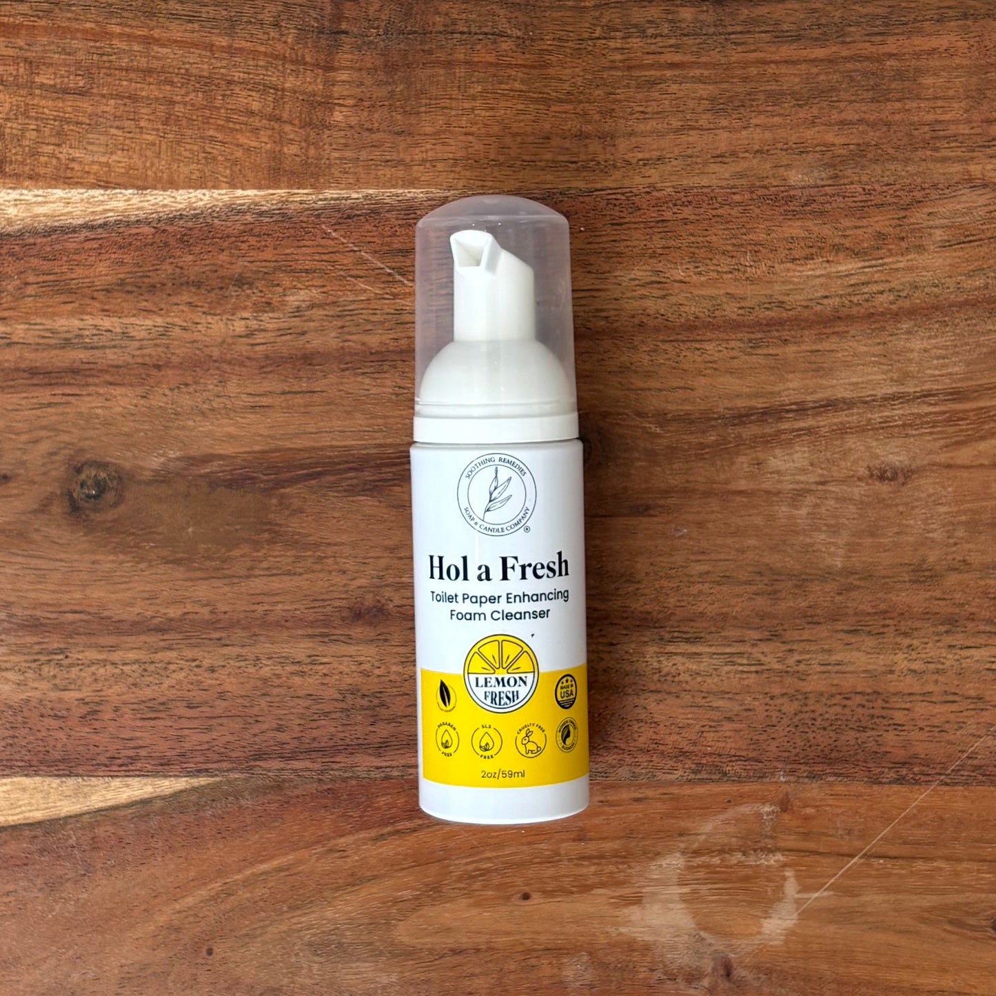 A bottle of Hol a Fresh toilet paper enhancer sits on a rectangular wooden cutting board,