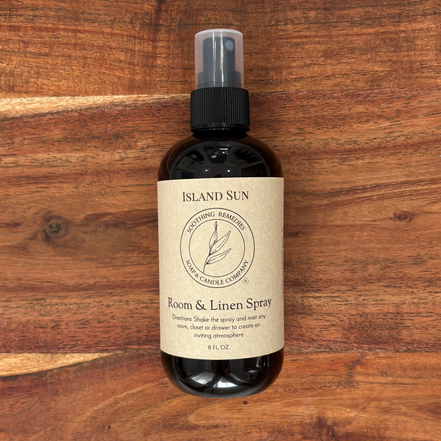 A bottle of Island Sun Room & Linen Spray placed on a rustic wooden board.