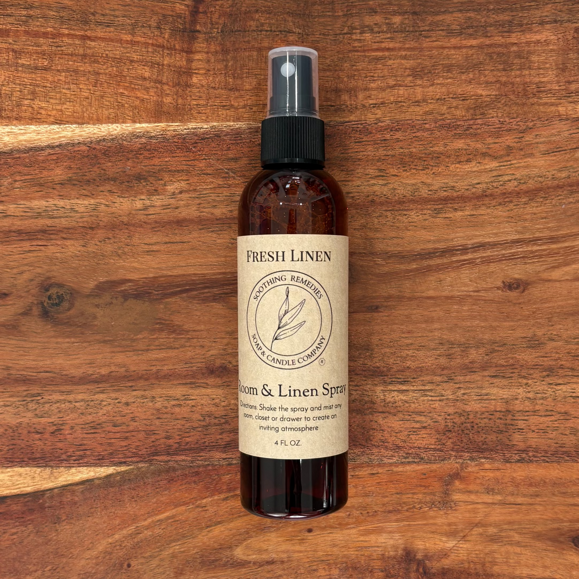 A bottle of Fresh Linen Germ & Linen Spray sits centered on a rustic wooden board.